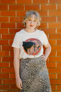 Image shows woman smiling in Artemis tee in Natural