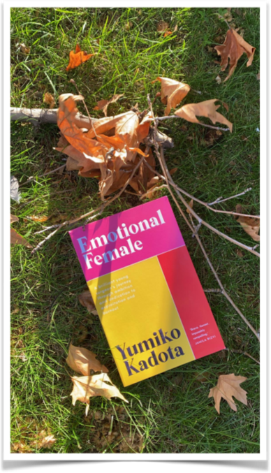 Photo of Yumiko Kadota's memoir, Emotional Female, laid on the grass with fallen autumn leaves